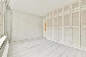 An empty room with white shutters and wooden floors photo