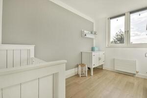A white room with a crib and a window photo