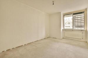 An empty room with a window and a radiator photo