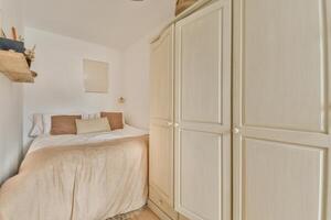 A small bedroom with a bed and a wardrobe photo