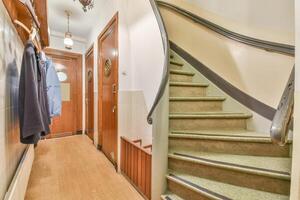A hallway with a staircase and a coat rack photo