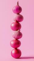 A stack of red onion balancing to top with solid bacground photo