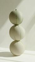 A stack of melon fruit balancing on top with solid background photo