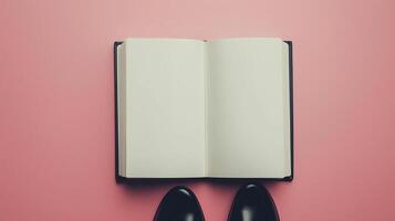 Blank white book open white paper and a pair black shoes top of view pink background photo