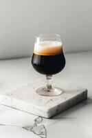 A glass of dark beer sitting on a marble counter photo