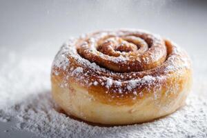 A cinnamon roll covered in powdered sugar photo