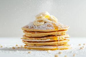 A stack of pancakes with powdered sugar and bananas photo