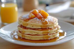 A stack of pancakes on a plate with syrup and orange juice photo