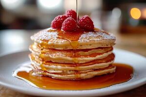 A stack of pancakes with syrup and raspberries photo
