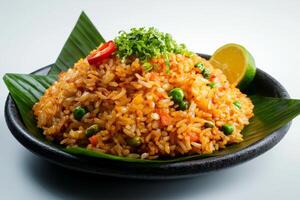 A plate of rice with vegetables and a lime wedge photo