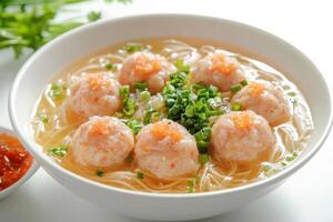 A bowl of soup with shrimp balls and green onions photo
