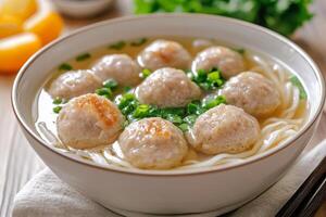 Chinese meatball soup with noodles and chopsticks photo