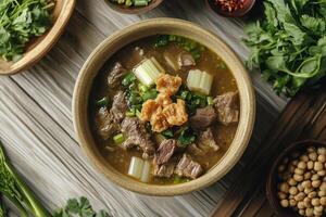 A bowl of beef and vegetables is served on a wooden table photo