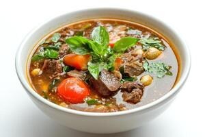 A bowl of soup with meat, vegetables and herbs photo