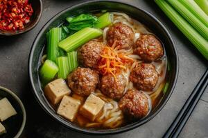 Chinese meatball soup with noodles and vegetables photo