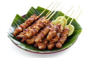Chicken satay on a leaf with a lime wedge photo
