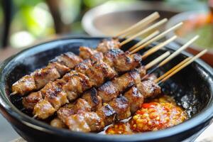 A bowl of meat on skewers with sauce photo