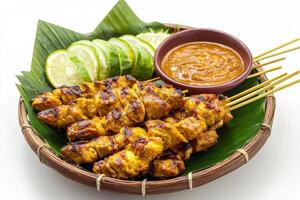 Chicken satay skewers with dipping sauce on a leaf photo