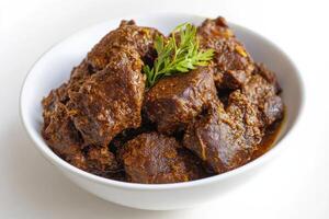 A bowl of beef stew with a sprig of rosemary photo