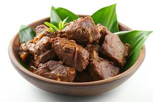 A bowl of meat and leaves sitting on a white table photo