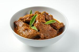 A bowl of meat and curry on a white surface photo