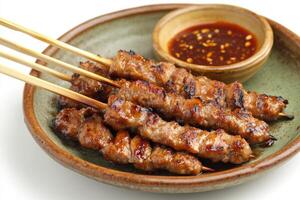 A bowl of meat on skewers with sauce photo