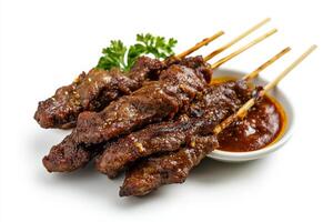 A plate of meat skewers with sauce on them photo