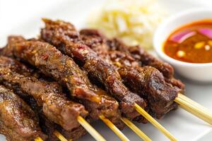 A plate of meat skewers with sauce on them photo