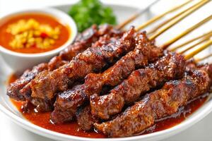 A plate of meat skewers with sauce on them photo