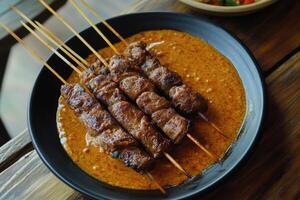 A plate of meat skewers on a wooden table photo