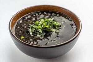 A bowl of black rice with green herbs in it photo