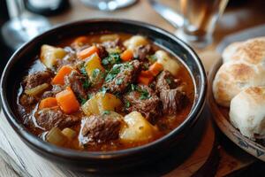 A bowl of stew with bread and a glass of beer photo