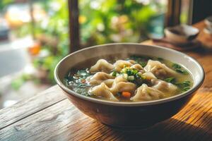 A bowl of soup with dumplings sitting on a wooden table photo