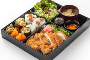 A black box with sushi, chicken, and vegetables photo