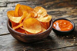 Potato chips in a bowl with ketchup on a wooden table photo
