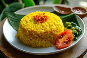 A plate of yellow rice with a tomato and green leaf photo