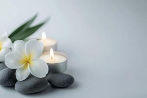 Spa stones and candles with frangipani flower on white background photo