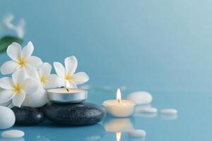 Spa stones and candles with flowers on blue background photo