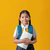 Portrait of a little girl in school uniform holding a notebook and smiling photo