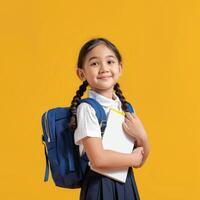 A little girl in school uniform holding a notebook and a backpack photo