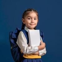 Portrait of cute little girl with school bag and notebook on blue background photo