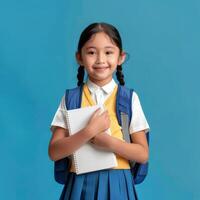 A little girl in a school uniform holding a notebook photo