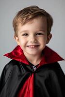A young boy in a black and red cape smiling photo