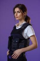 A woman in a police vest posing against a purple background photo