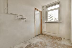 An empty room with a window and a toilet photo