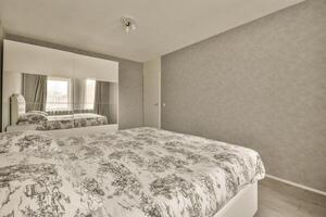 A bedroom with a bed, a mirror and a wall photo