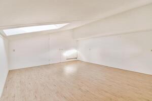 A room with a skylight and a wooden floor photo