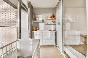 A white nursery with a crib, dresser and mirror photo