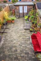 A brick patio with a red couch and a table photo