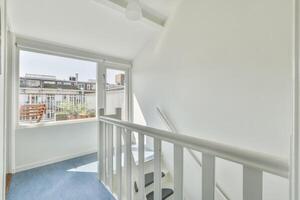 A white railing leads to a balcony with a view of the city photo